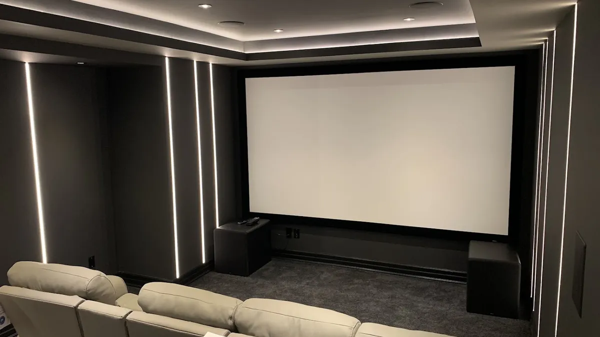 Dedicated home theatre with a large projection screen, vertical LED wall lighting and a row of leather recliners