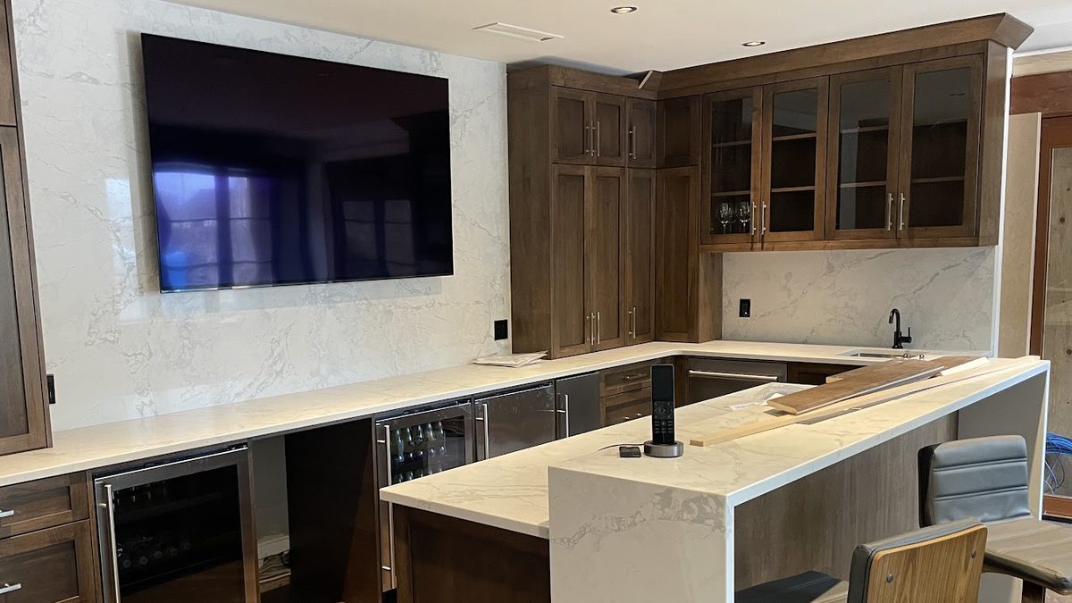 Home bar with a wall-mounted TV and a handheld system remote on its charging base